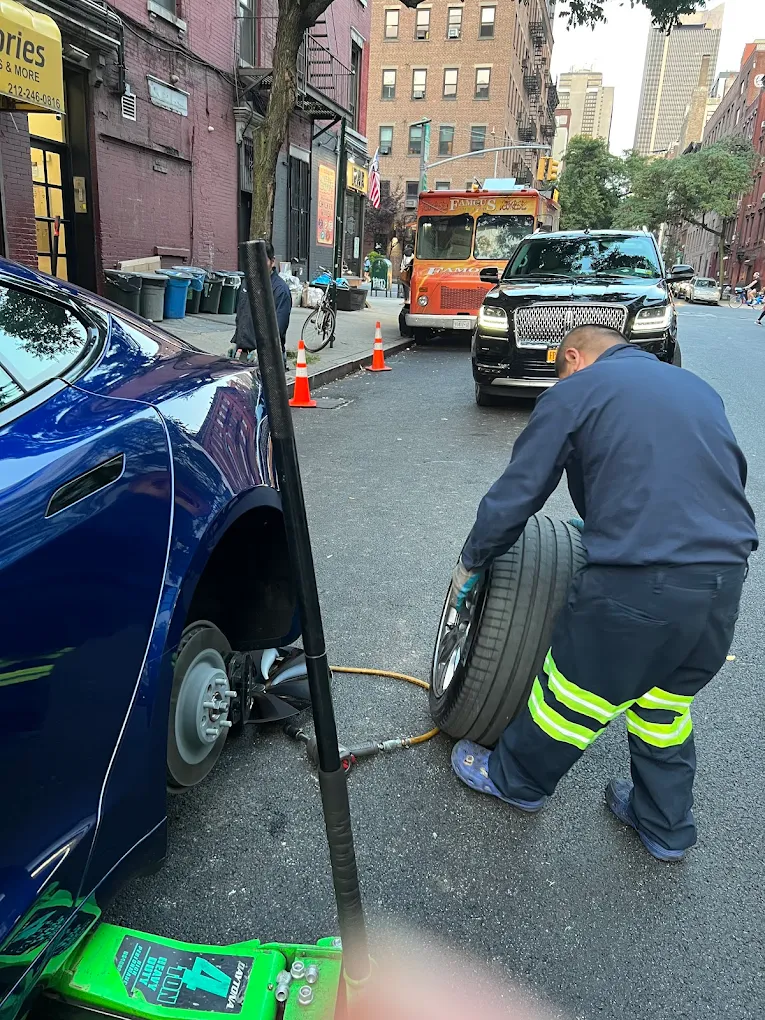 Mechanic changing tire on Tesla in Hell's Kitchen street